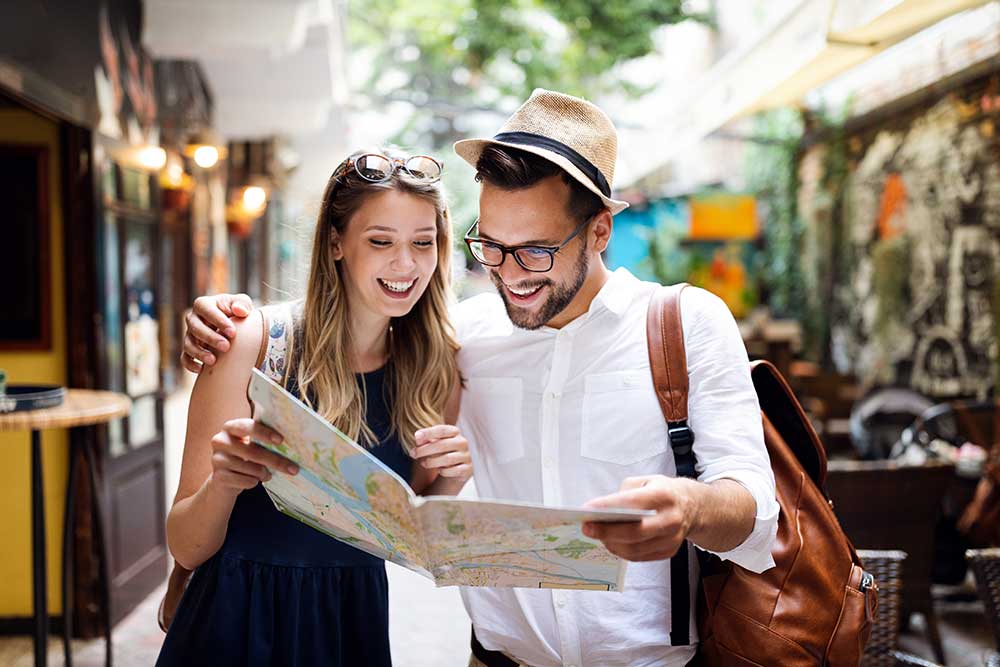 Organización de viajes para grupos - pareja de turistas consultando un mapa durante sus vacaciones