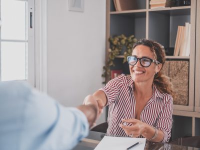 Smiling caucasian female hr manager handshake hire male candidate at job interview Mujer sonriente estrechando la mano de un cliente con atención personalizada para la organización de eventos para empresas