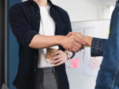 Two people shaking hands in a business setting. Concept of professionalism Apretón de manos para un acuerdo personalizado de la organización de eventos empresariales a medida